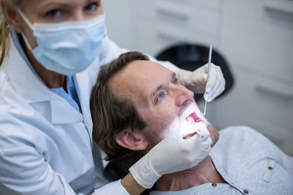 Dentista examinando um paciente com ferramentas — Fotografia de Stock