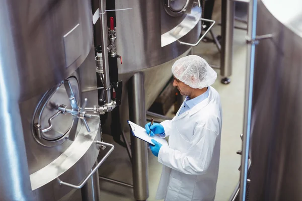 Fabricante de pie en medio de tanques de almacenamiento en la fábrica de cerveza — Foto de Stock