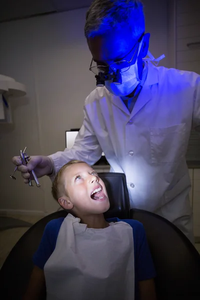 Dentiste examinant un jeune patient avec des outils — Photo