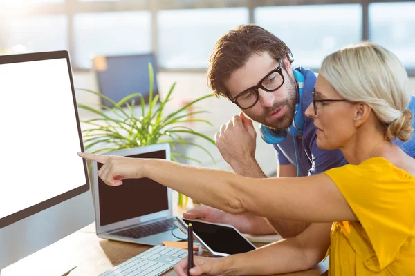 Graphic designers interacting while working on computer — Stock Photo, Image