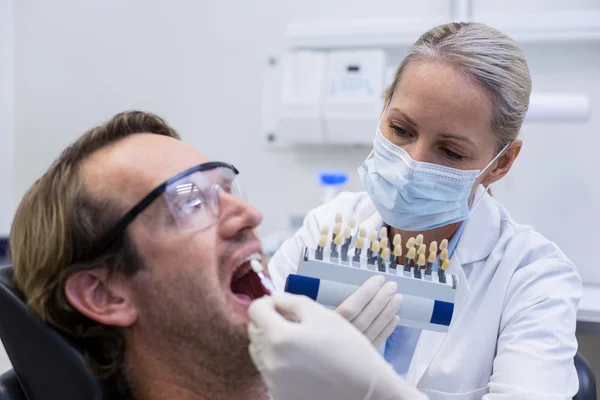 Female dentist examining male patient with teeth shades — Stock Photo, Image