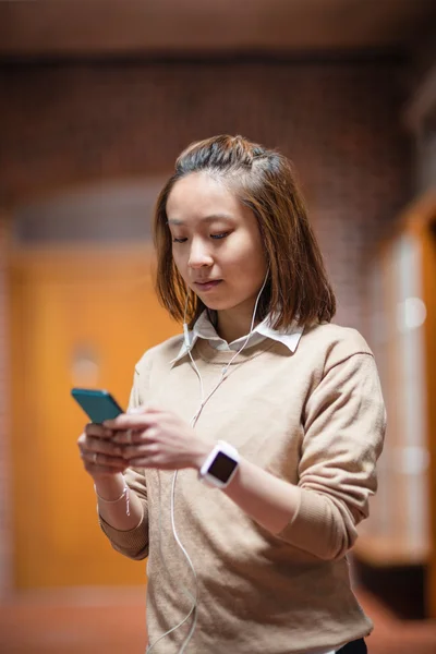 Jonge vrouw met behulp van mobiele telefoon in gang — Stockfoto