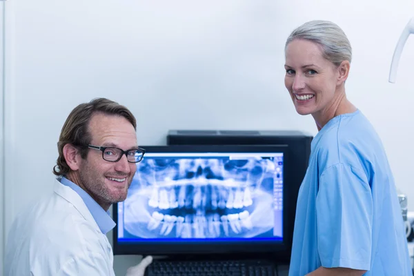 Οδοντίατρο και οδοντιατρική Βοηθός συζητώντας μια ακτινογραφία στην οθόνη — Φωτογραφία Αρχείου