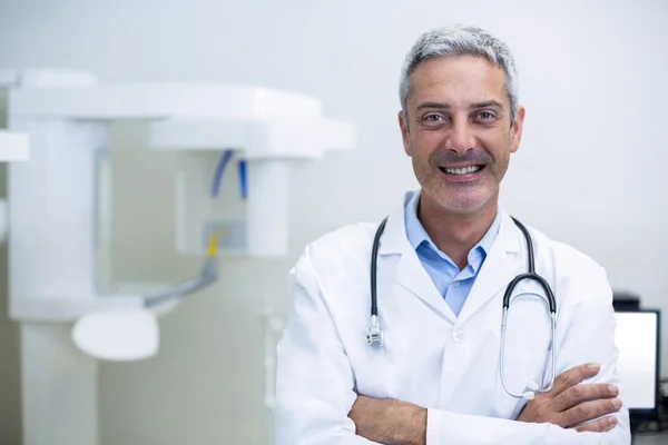 Dentista sorridente in piedi in clinica dentale — Foto Stock