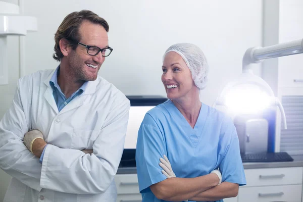 Uśmiechający się dentysty i asystent dentystyczny, stojąc z rękami skrzyżowanymi — Zdjęcie stockowe