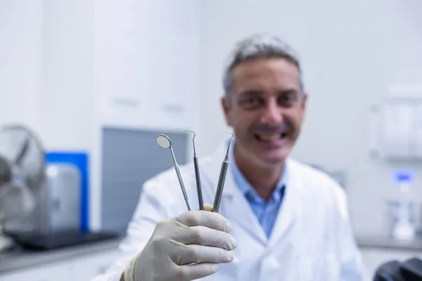 Портрет усміхненого стоматолога, що тримає зубні інструменти — стокове фото