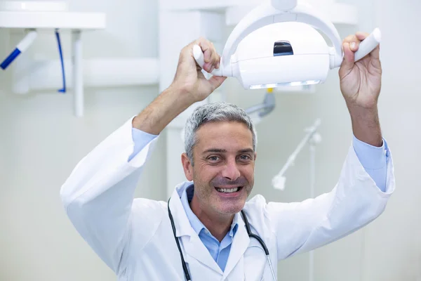 Smiling dentist adjusting light — Stock Photo, Image