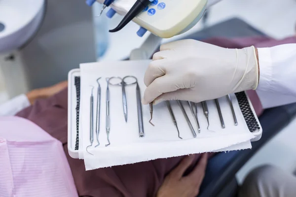 Dentista recogiendo herramientas dentales para examinar a un paciente — Foto de Stock