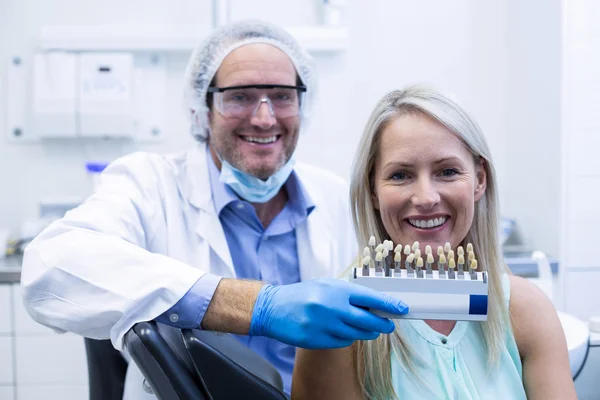 Zubař drží zuby odstínů při ženských pacientů s úsměvem — Stock fotografie