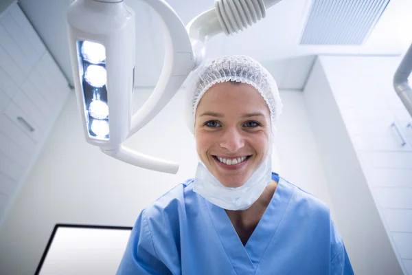 Assistente dentário sorrindo para a câmera ao lado da luz — Fotografia de Stock