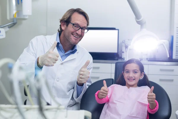 Lächelnder Zahnarzt und junge Patientin zeigen Daumen hoch — Stockfoto