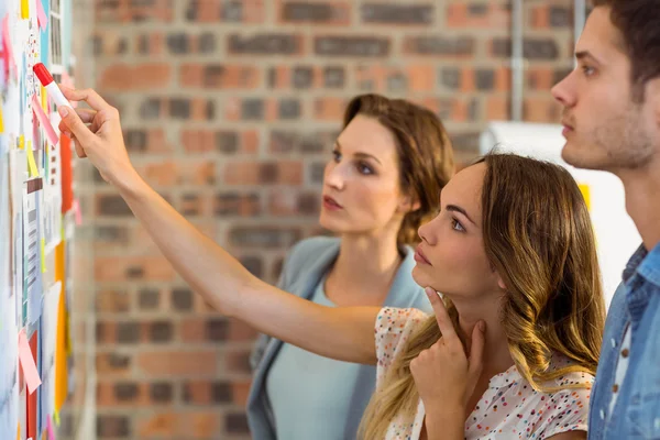 Business executives looking at sticky notes on whiteboard — Stock Photo, Image