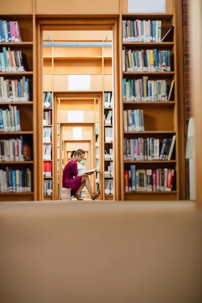 Giovane donna che legge libro in biblioteca — Foto Stock