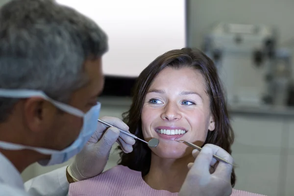 Tandläkaren undersöker en kvinnlig patient med verktyg — Stockfoto