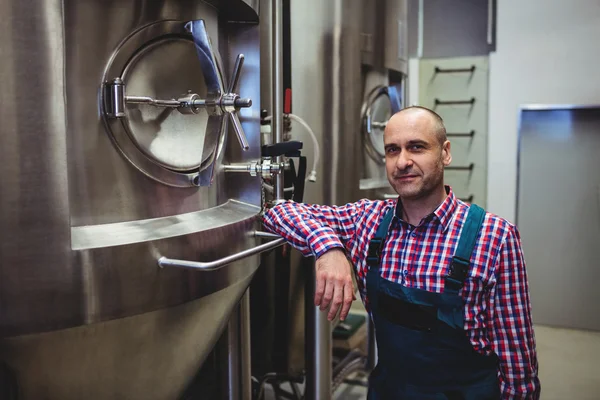 Volwassen fabrikant staande door opslagtanks in brouwerij — Stockfoto