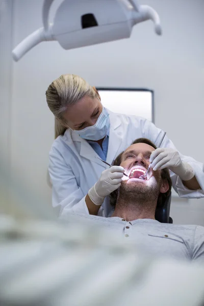 Dentista examinando a un paciente con herramientas — Foto de Stock