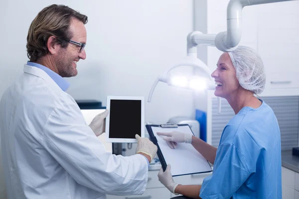 Стоматолог и зубной ассистент, работающий над цифровым планшетом — стоковое фото