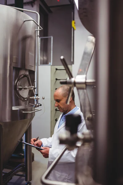 Зрілий виробник стоїть серед резервуарів для зберігання на пивоварні — стокове фото