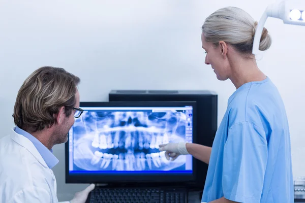 Dentysta i asystent dentystyczny, omawiając RTG na monitorze — Zdjęcie stockowe