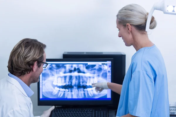 Odontoiatra e assistente dentista che discutono una radiografia sul monitor — Foto Stock