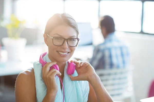 Business executive holding headphones in office — Stock Photo, Image