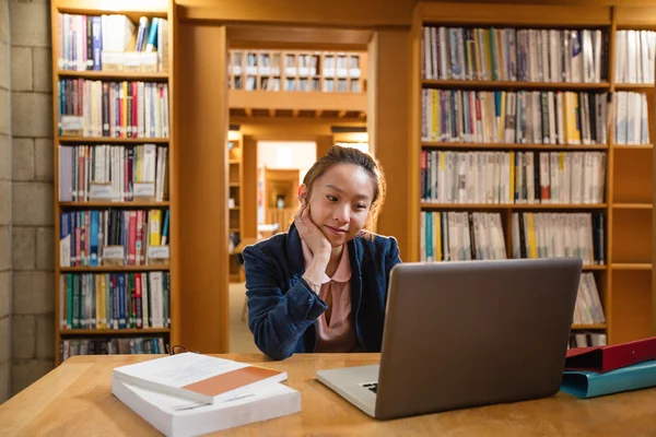 Young woman using laptop in library — Stock Photo, Image