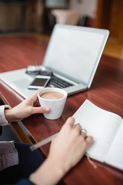 Vrouw in boek schrijven terwijl het hebben van thee — Stockfoto