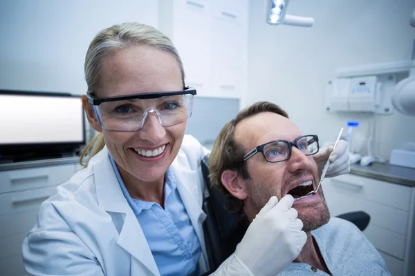 Dokter gigi wanita memeriksa pasien pria dengan alat-alat — Stok Foto