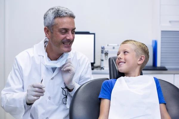 Улыбающийся дантист разговаривает с молодым пациентом — стоковое фото