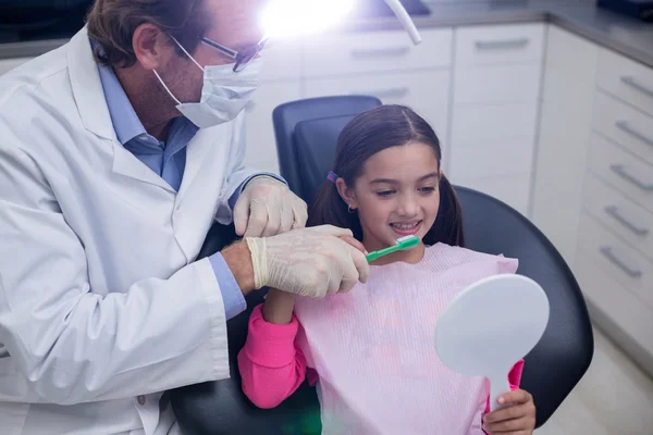 Dentista assistindo paciente jovem enquanto escova os dentes — Fotografia de Stock