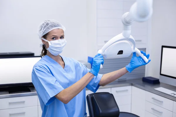 Sonriente asistente dental ajustando la luz —  Fotos de Stock