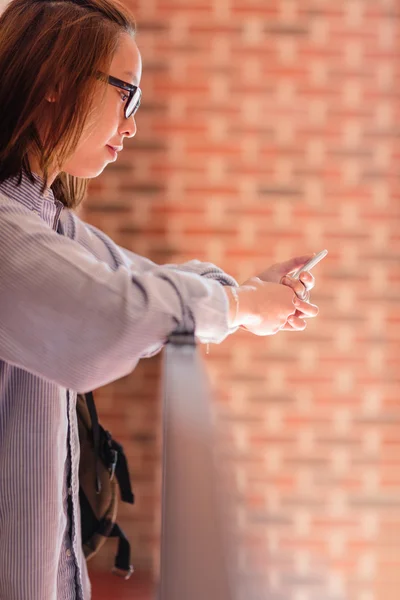 Jeune femme utilisant un téléphone portable dans le couloir — Photo
