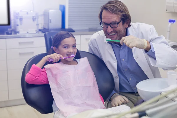 Dentista sorridente e paciente escovando os dentes — Fotografia de Stock