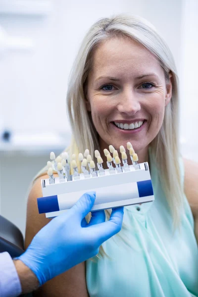 Dentista segurando tons de dentes enquanto o paciente do sexo feminino sorrindo — Fotografia de Stock