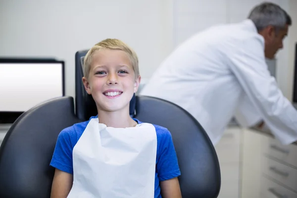 微笑着年轻患者坐在牙医的椅子上 — 图库照片