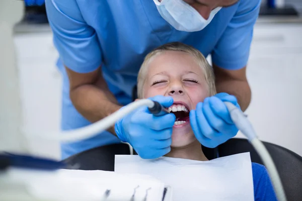 Dentista examinando a un paciente joven con herramientas — Foto de Stock