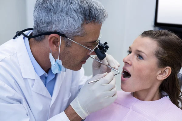 Dentista examinando a una paciente con herramientas dentales — Foto de Stock