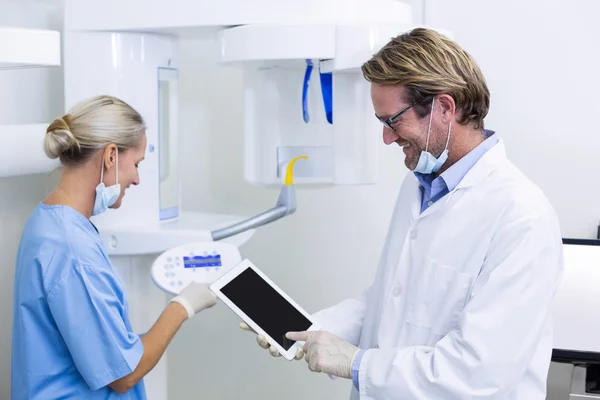 Zahnarzt und Zahnarzthelferin arbeiten an digitalem Tablet — Stockfoto