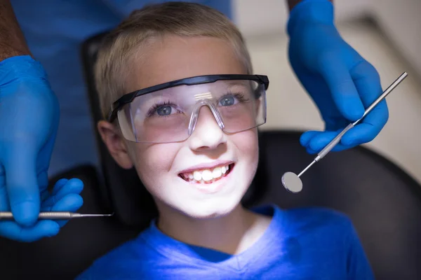 Dentiste examinant un jeune patient avec des outils — Photo