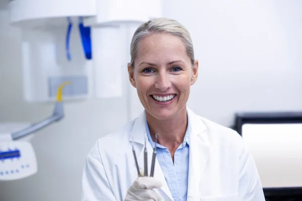 Retrato del dentista femenino sosteniendo herramientas dentales —  Fotos de Stock