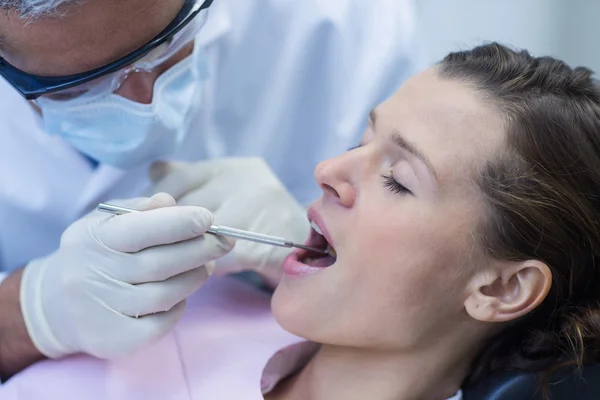 Dentista examinando a un paciente con herramientas — Foto de Stock