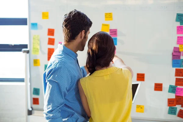 Business executive and co-worker looking at sticky notes — Stock Photo, Image