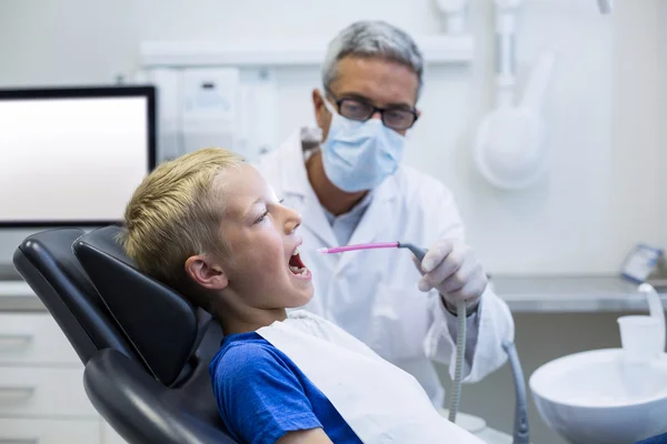 Dentista examinando um paciente jovem com ferramentas — Fotografia de Stock