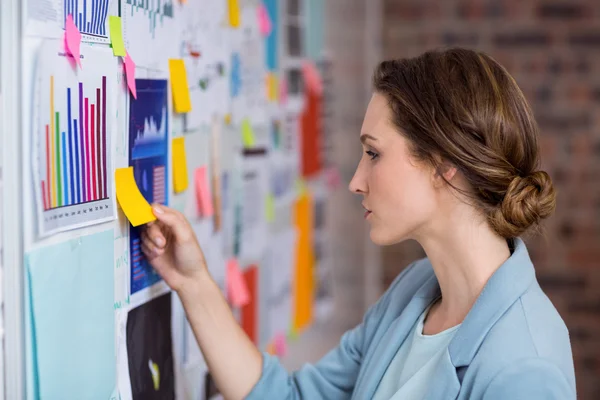 Businesswoman putting sticky notes on whiteboard — Stock Photo, Image