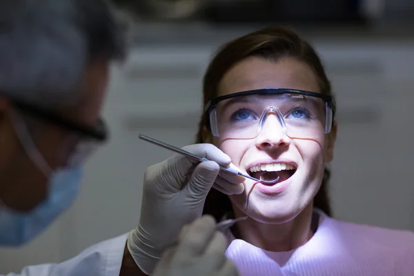 Dentista examinando a una paciente con herramientas — Foto de Stock