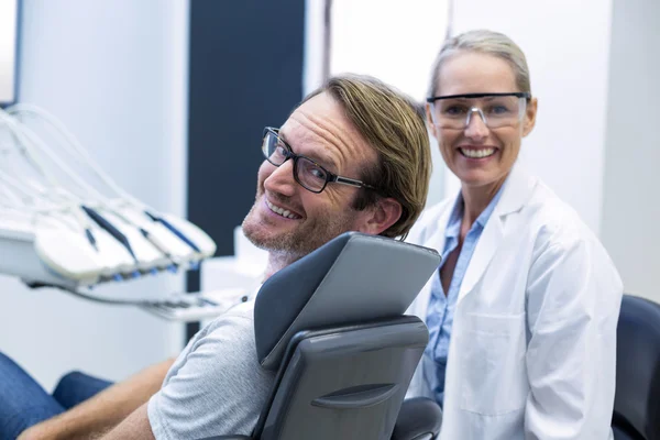 Dentista feminino e paciente do sexo masculino sorrindo — Fotografia de Stock