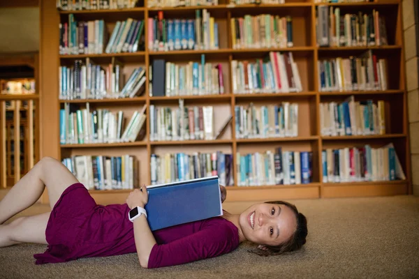 Mujer joven acostada en el suelo en la biblioteca — Foto de Stock