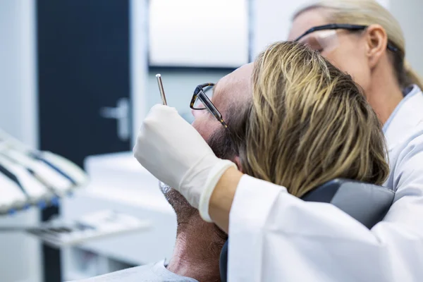 Dentista feminina examinando paciente masculino com ferramentas — Fotografia de Stock