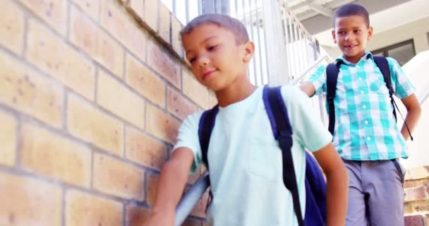 Улыбающиеся школьники идут по лестнице в школе — стоковое видео