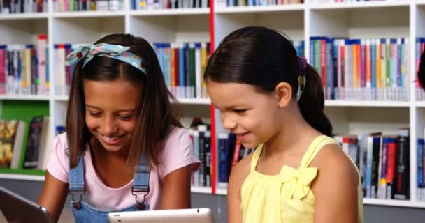 Niños de la escuela usando tableta digital en la biblioteca — Vídeos de Stock